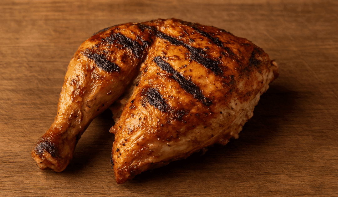 Medio pollo al carbón con piel crujiente y marcas de parrilla, presentado sobre tabla de madera rústica en el Asador AR TANGO de Montequinto.